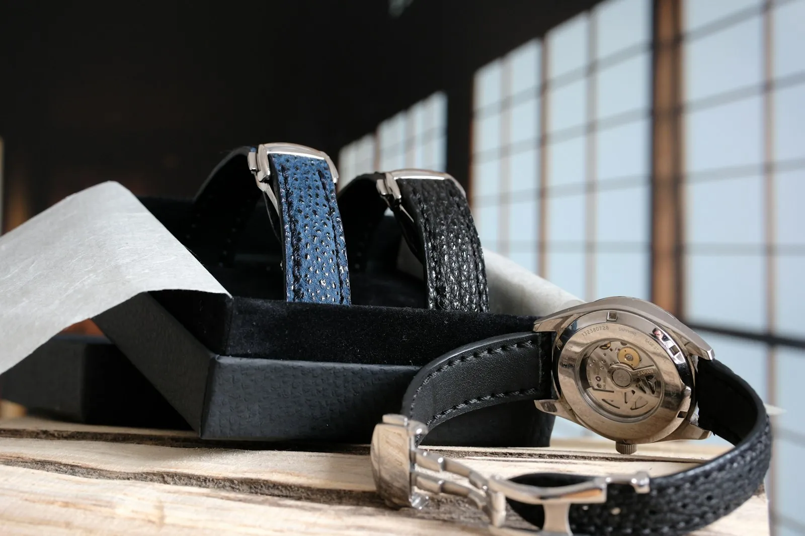 Une montre posée dans un coffret avec deux bracelets en cuir de rechange