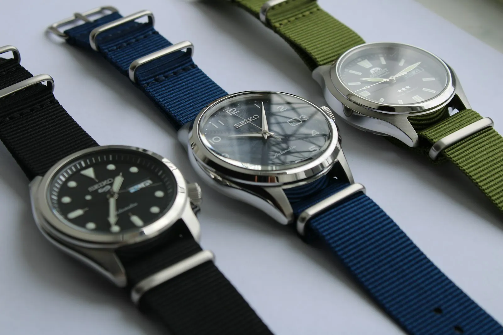 Trois montres sur bracelets NATO noir, bleu et vert